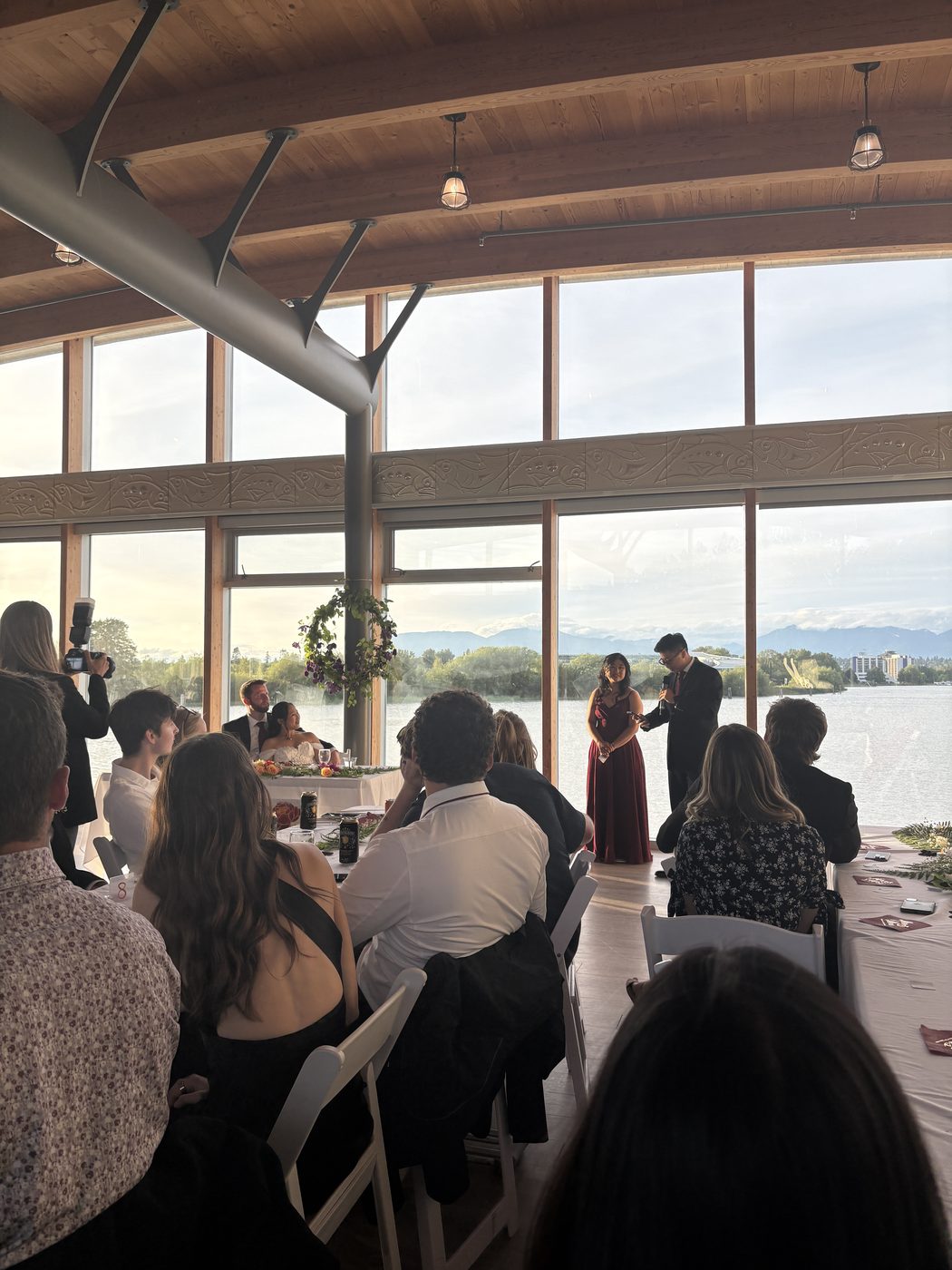 Guests seated for speeches, a lake and mountains through the windows