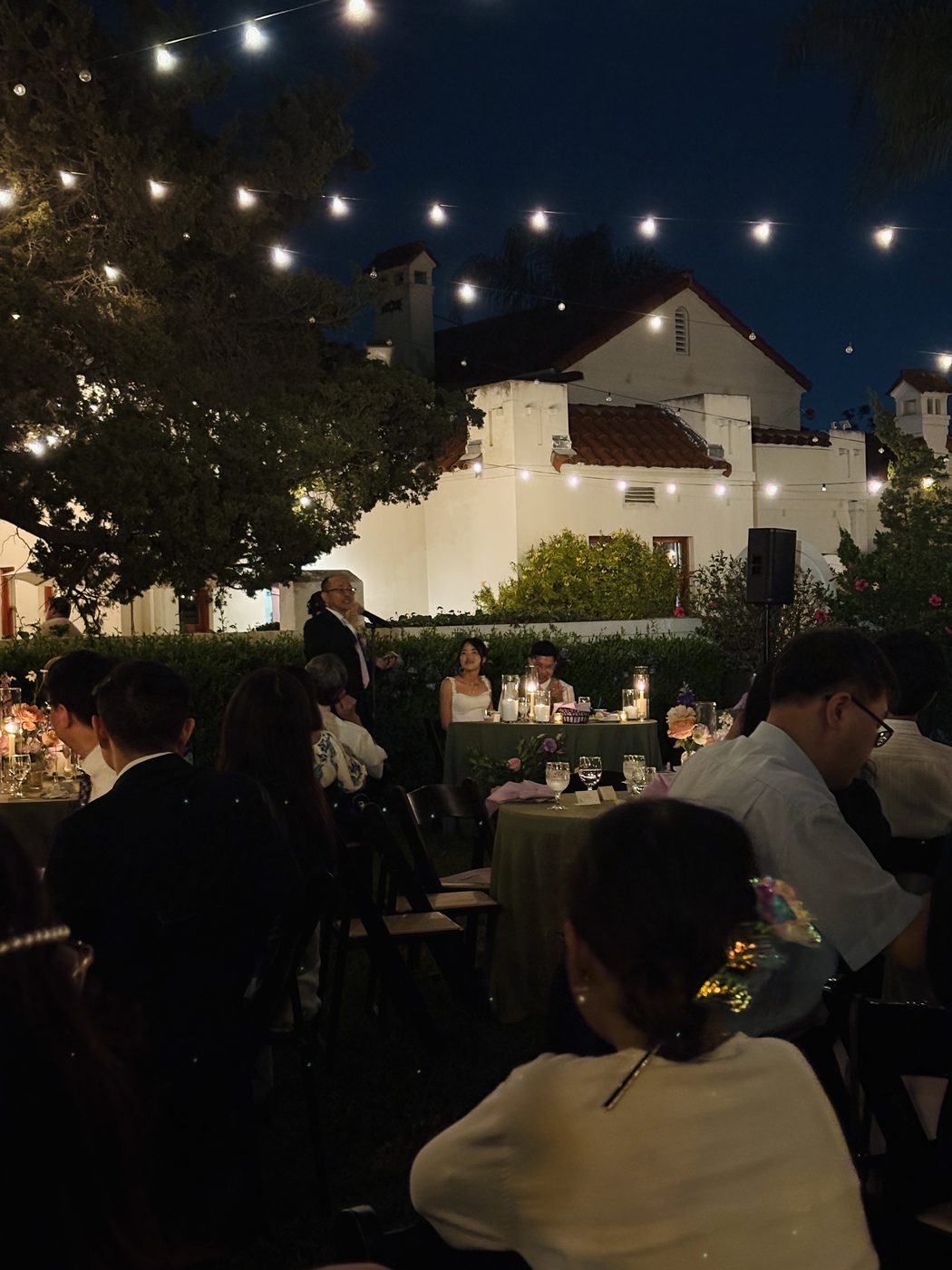 An outdoor reception at night, string lights strung over the tables