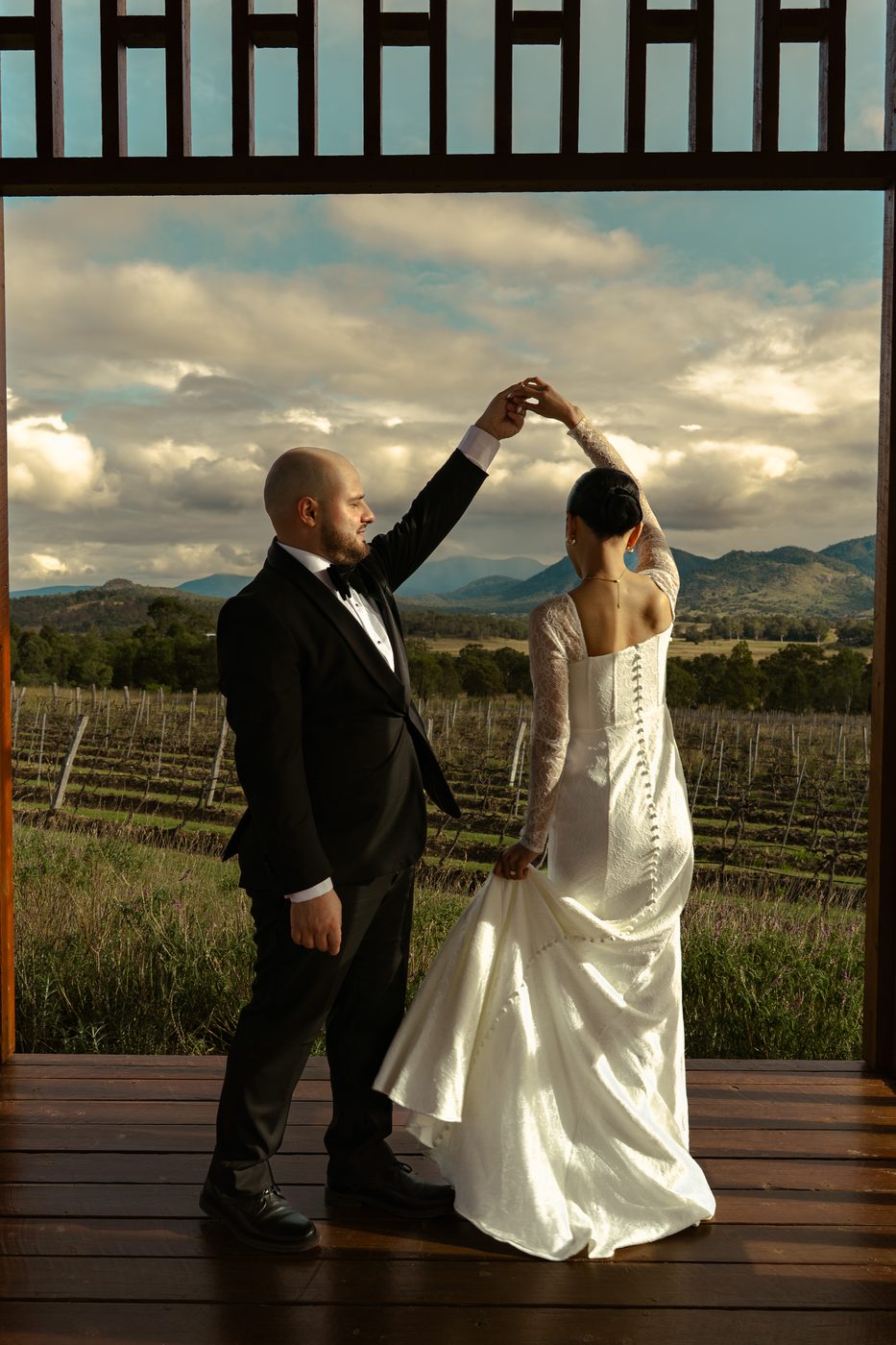 A groom twirling his bride on a deck above the vines